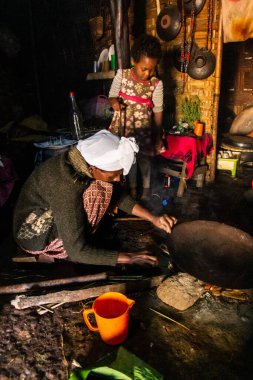 DORZE, ETHIOPIA - 30 HAZİRAN 2020 Dorze kadını bambu, Etiyopya 'dan örülmüş geleneksel bir kulübede ensetten yapılmış koçolu ekmek hazırlıyor