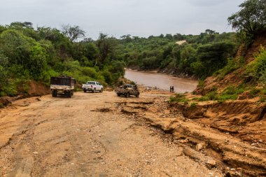 OMO VALLEY, ETHIOPIA - 4 Şubat 2020: Etiyopya, Etiyopya 'daki Kizo nehri boyunca bir nehrin önünde bekleyen araçlar