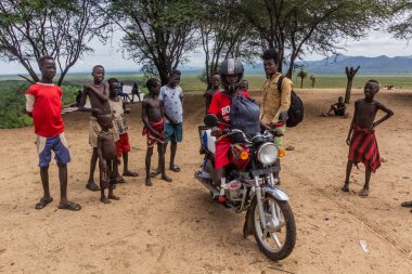 KORCHO, ETHIOPIA - 4 Şubat 2020: Korcho köyündeki Karo kabilesinin çocukları ve Etiyopya 'da motosikletle dışarıdan gelen ziyaretçiler
