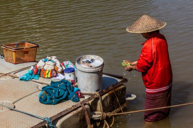 MUANG NGOI NEUA, LAOS - NOVEMBER 25, 2019: Local woman doing laundry in Nam Ou river in Muang Ngoi Neua village, Laos clipart