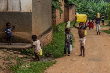 BUDADIRI, UGANDA - 25 Şubat 2020: Budadiri köyünde su taşıyan çocuklar, Uganda
