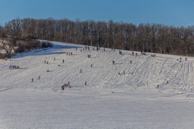 DLOUHONOVICE, CZEHIA - 13 Şubat 2021: İnsanlar Çek Cumhuriyeti 'nin Dlouhonovice yakınlarında karlı bir tepenin keyfini çıkarıyorlar