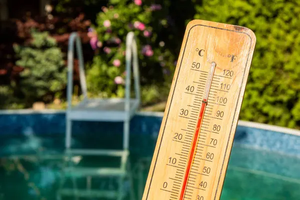 stock image Thermometer displaying high summer temperature on a swimming pool background