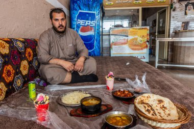 DHAHRAN AL JANUB, SAUDI ARABIA - 25 Kasım 2021: Dhahran al Janub, Suudi Arabistan 'da bir restoranda öğle yemeği yiyen yerel bir adam