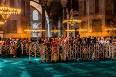 İSTANBUL, TURKEY - 19 Eylül 2022: İstanbul, Türkiye 'deki Ayasofya Tapınağı' nda namaz sırasında çitin arkasındaki turistler