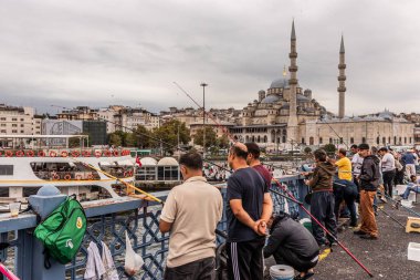 İSTANBUL, TURKEY - 18 Eylül 2022: İstanbul, Türkiye 'deki Galata köprüsünde balıkçılar. Arka planda Yeni Cami (Yeni Camii).