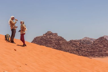 WADI RUM, JORDAN - 13 Temmuz 2022: Wadi Rum Çölü 'nde bir kum tepesinde turistler, Ürdün