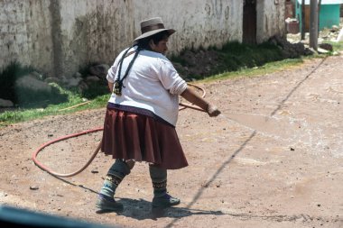 TINTINCO, PERU - 7 Kasım 2022 Yerel kadın Vinicunca Gökkuşağı Dağı, Peru 'ya giden çakıllı bir yola püskürtüyor