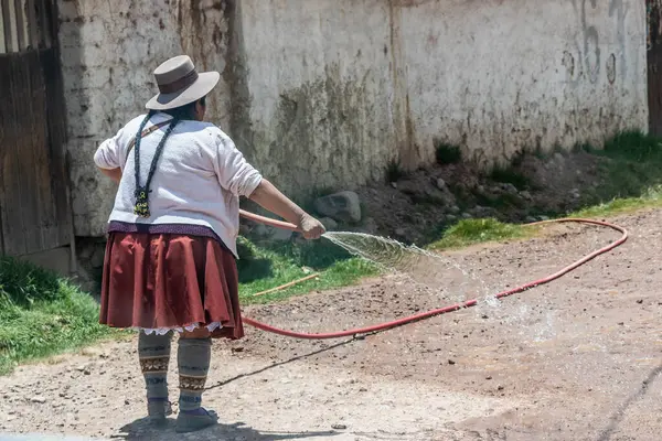 TINTINCO, PERU - 7 Kasım 2022 Yerel kadın Vinicunca Gökkuşağı Dağı, Peru 'ya giden çakıllı bir yola püskürtüyor