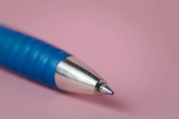 Closeup image of the pointed end part of a pen on pink background for the concept of work and study.