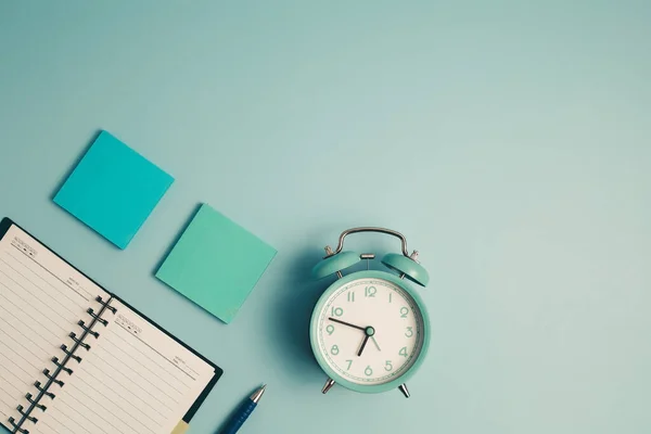 時間管理の概念のための青の背景に日記ノートやその他の作業や教材と目覚まし時計 — ストック写真