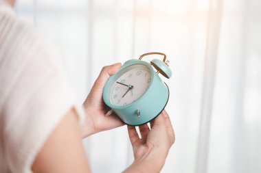 Asyalı bir kadının saati hatırlatmak ya da zaman yönetimi kavramına alarm kurmak için ayarlıyor.
