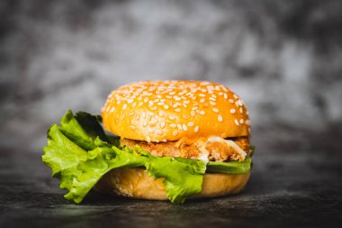 Pastane, yemek ve yeme konsepti için koyu arkaplanda lezzetli bir hamburger.
