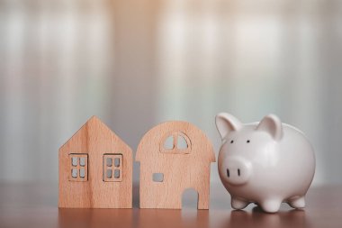 İş, finans, tasarruf ve emlak yatırım konsepti için masada ahşap ev modeli ile domuz kumbarası tasarruf.