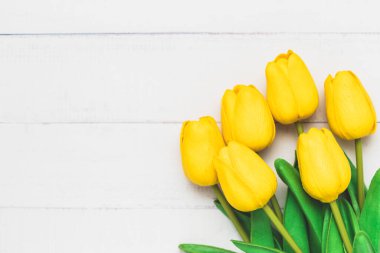 Doğa dekorasyonu ve ilkbahar konsepti için beyaz masa zemininde suni sarı lalelerin üst görünümü