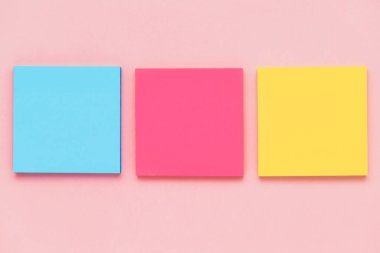 Ofis ve okul sabit konsepti için pembe arkaplan üzerine yapışkan kağıt notların üst görünümü