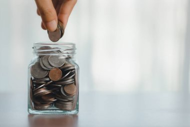 Bozuk paralarla dolu cam kavanoz, el tasarrufu parası, finansal büyüme, para birimi, kap ve insan dokunuşunun bileşenlerini birleştiren bir iş konseptini tasvir ediyor