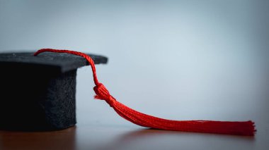 Beyaz arka planda kırmızı püsküllü mezuniyet şapkası. Mezuniyet teması için akademik başarı, eğitim, üniversite, başarı, tören ve kopya alanı sembolü.