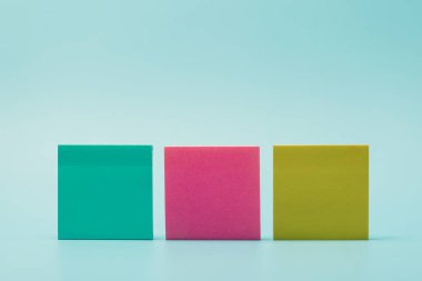 Mavi arka planda düzenlenmiş renkli yapışkanlı kağıtlar. Hatırlatma, beyin fırtınası, organizasyon, verimlilik, ofis işi ve yaratıcı planlama kavramı.