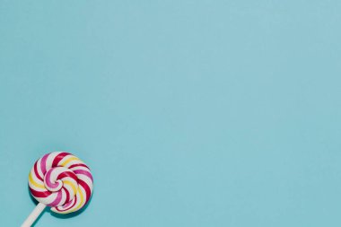 Yatıştırıcı mavi bir arka planda canlı pembe, sarı, beyaz kıvrımlı lolipop. Tatlılık, çocukluk, neşe, ikramlar, basit zevkler için mükemmel..