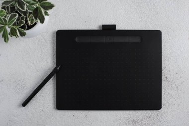 Beyaz arka planda stili olan grafik tablet. Yakınlarda beyaz bir saksıda bir bitki var..