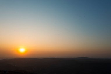 Dağların zirvesi ve günbatımı gökyüzü ile güzel sisli bir manzara.