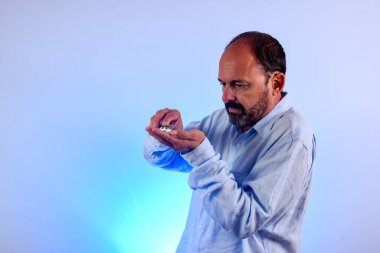 Altmış yaşında bir adam elinde ilaç tutuyor.