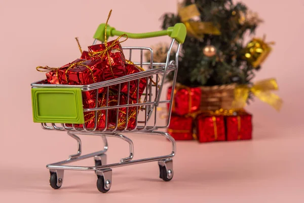 Karácsonyi Bevásárlókosár Ajándékokkal Karácsonyfa Háttérben Világos Piros Háttér Szelektív Fókusz — Stock Fotó