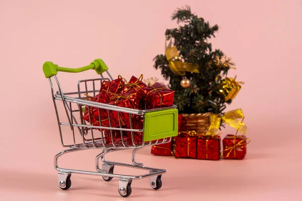 Karácsonyi Bevásárlókosár Ajándékokkal Karácsonyfa Háttérben Világos Piros Háttér — Stock Fotó