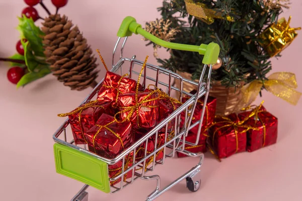 Karácsonyi Bevásárlókosár Ajándékokkal Karácsonyfa Háttérben Világos Piros Háttér — Stock Fotó