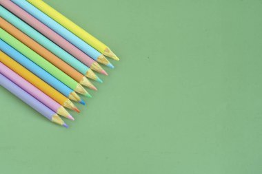 Pastel colored pencils, top view on green background, illustration concept, background and education and back to school