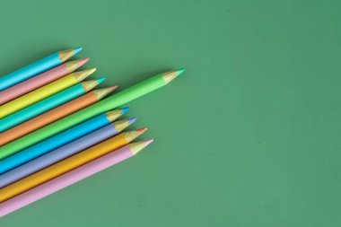Pastel colored pencils, top view on green background, illustration concept, background and education and back to school
