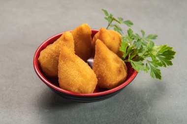 traditional fried coxinha in plate on slate background, popular brazilian snack served at parties