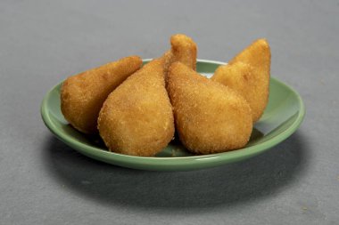 traditional fried coxinha in plate on slate background, popular brazilian snack served at parties
