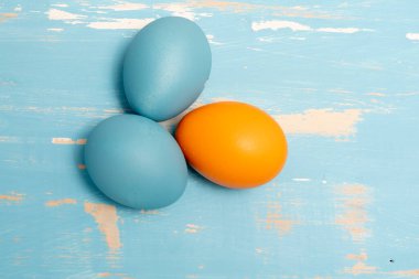 Paskalya bayramını sembolize eden yumurtalar mavi ve turuncu renkte aynı renk ahşap arka planda.