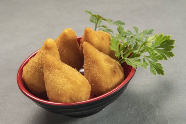 traditional fried coxinha in plate on slate background, popular brazilian snack served at parties