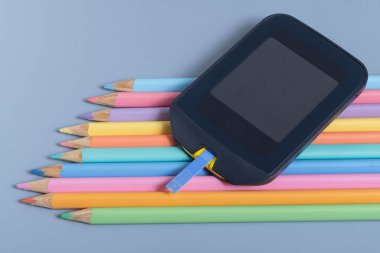 Back to school concept for kids with diabetes represented by colored pencils and glucometer