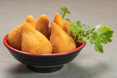 traditional fried coxinha in plate on slate background, popular brazilian snack served at parties