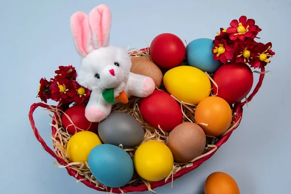 stock image basket with straw, bunny and eggs decorated for the celebration of Christian Easter in light background