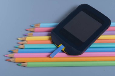 Back to school concept for kids with diabetes represented by colored pencils and glucometer