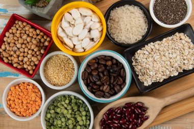 Kâselerdeki farklı baklagiller, yeşil ve sarı bezelyeler, nohutlar, renkli fasulyeler ve mercimek, üst manzara.