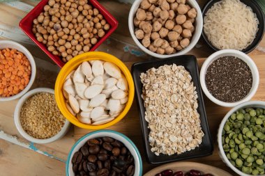 Kâselerdeki farklı baklagiller, yeşil ve sarı bezelyeler, nohutlar, renkli fasulyeler ve mercimek, üst manzara.