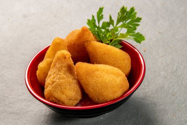 traditional fried coxinha in plate on slate background, popular brazilian snack served at parties