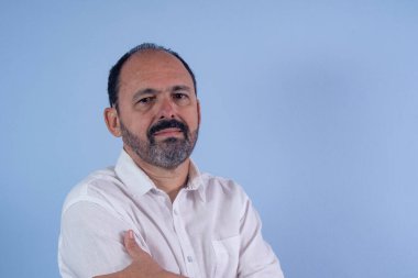 Mavi arka planda 60 yaşında sakallı bir adamın portresi.