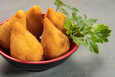 traditional fried coxinha in plate on slate background, popular brazilian snack served at parties