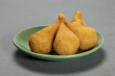traditional fried coxinha in plate on slate background, popular brazilian snack served at parties