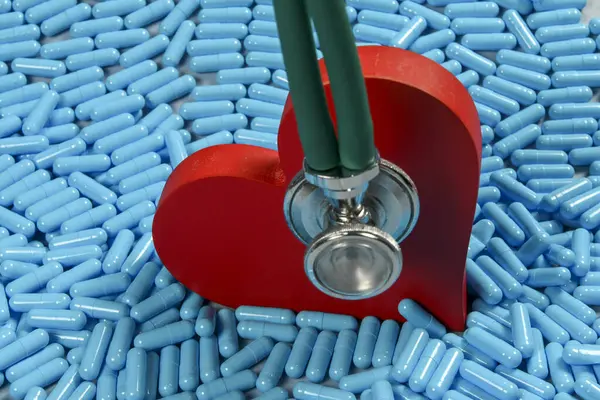 heart shape and medicine capsules representing heart problems and conventional treatment