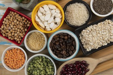 Kâselerdeki farklı baklagiller, yeşil ve sarı bezelyeler, nohutlar, renkli fasulyeler ve mercimek, üst manzara.