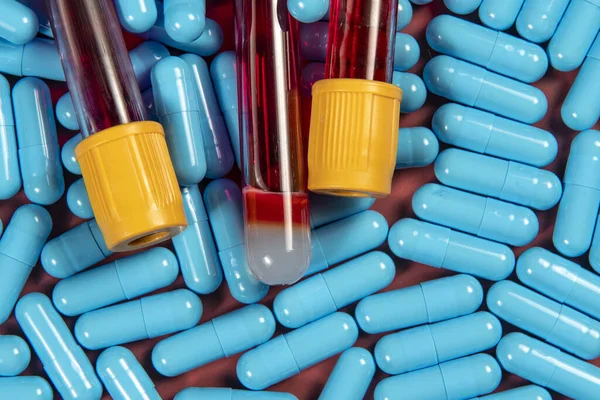 blue medicine capsules and blood test tube symbolizing preventive medicine