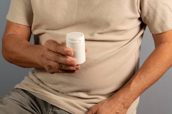 Hand holding bottle of pills representing different diseases. At home, indoors. front point of view